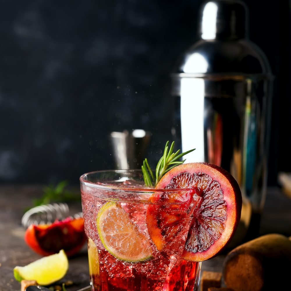 Blood Orange Margarita coctail with ice and thyme on dark backgorund