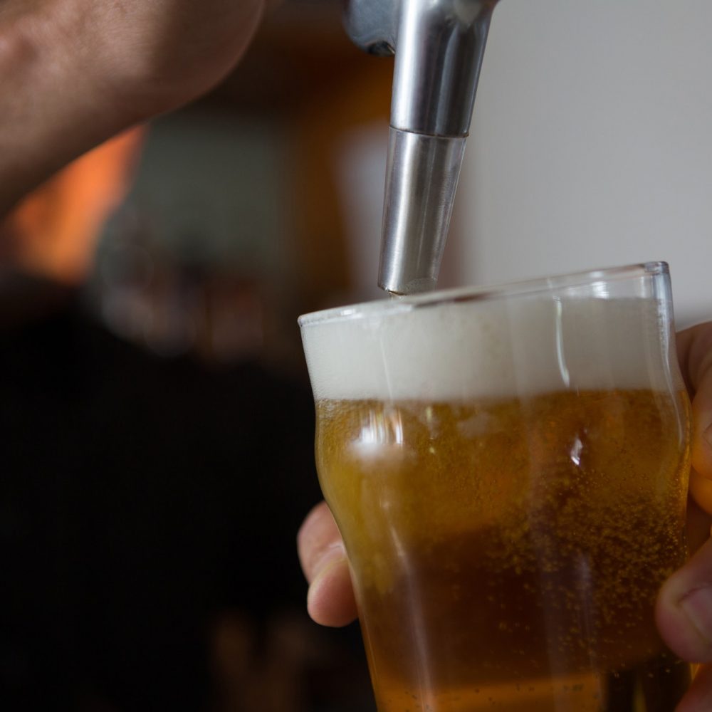 Brewer filling beer in beer glass from beer pump in bar